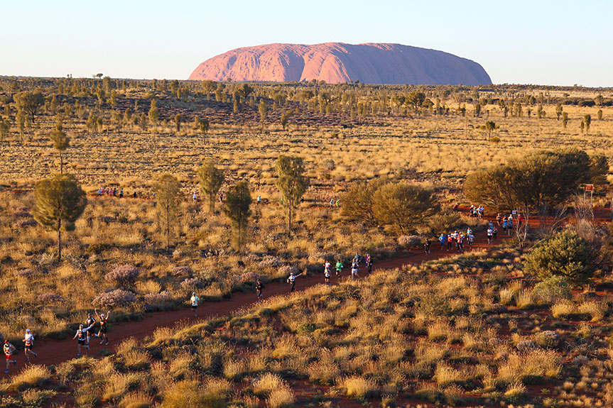 Runners compete in the Australian Outback Marathon with Uluru in the background