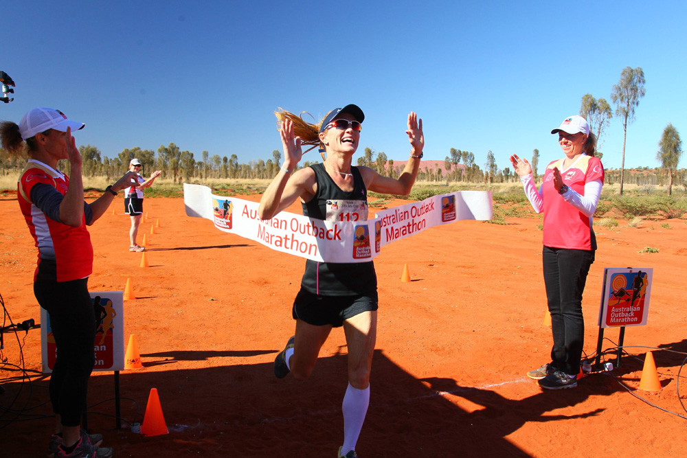 A woman crosses the finish line at the Australian Outback Marathon