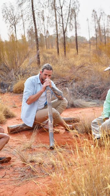 Man learning to play didgeridoo