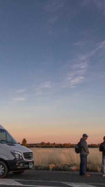 A couple standing beside a van with Ayers Rock in the background